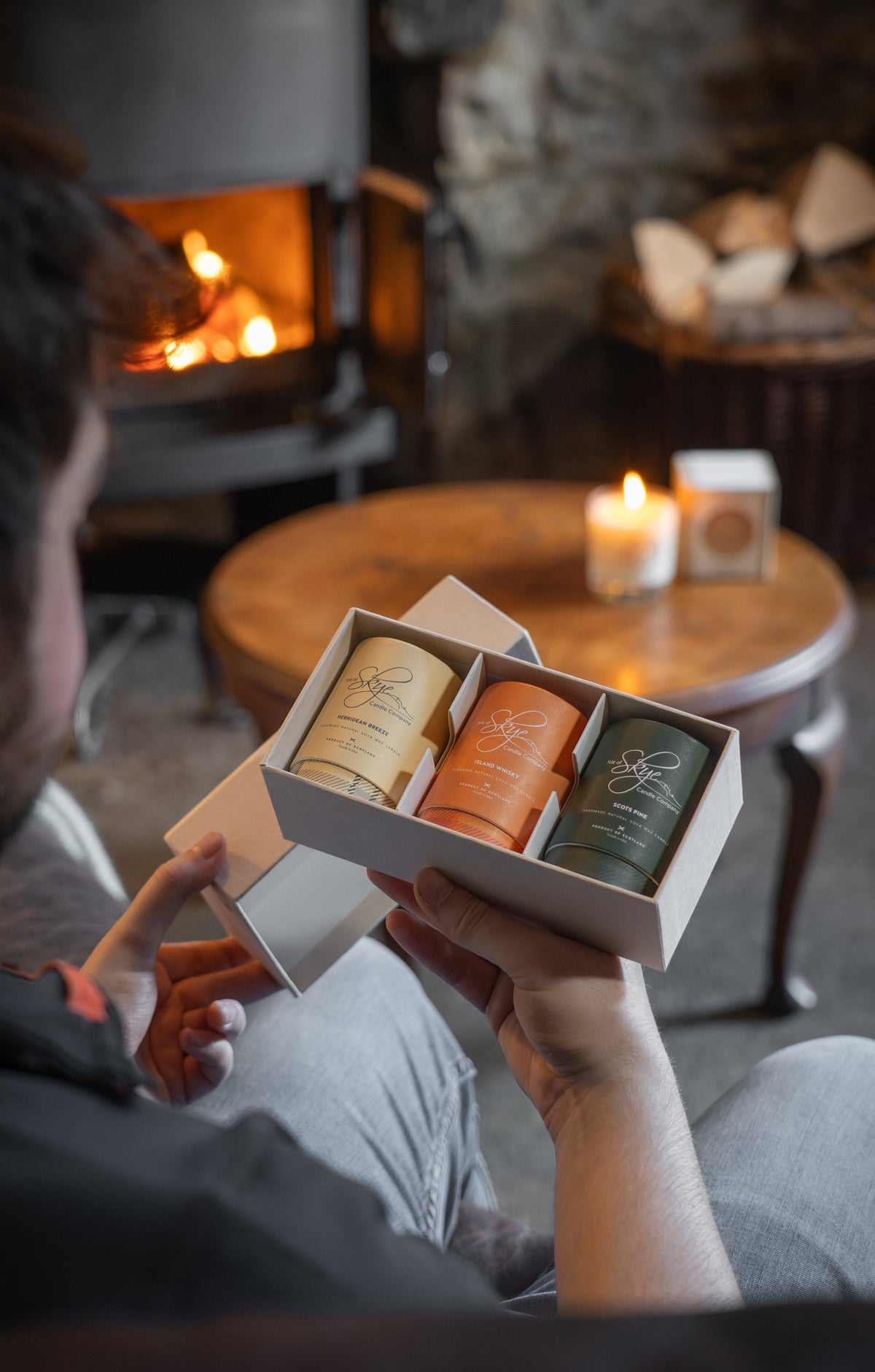 Male holding Isle of Skye candle gift set in a cosy pub environment. Gift set features three miniature candles.